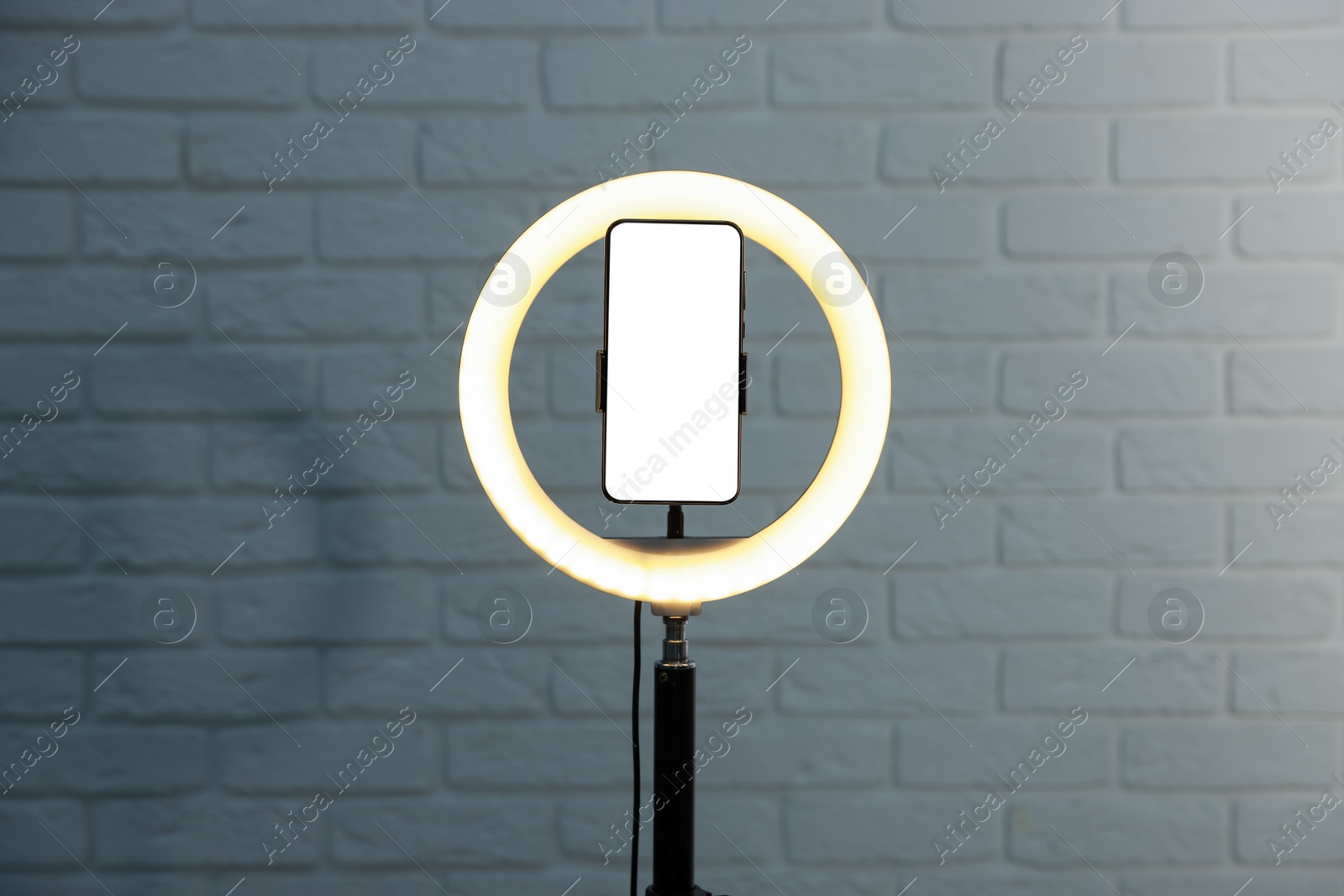 Photo of Ring lamp with smartphone against brick wall