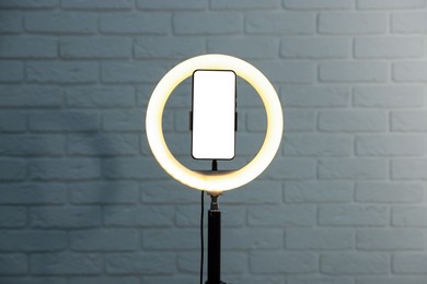 Photo of Ring lamp with smartphone against brick wall