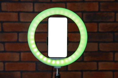 Photo of Ring lamp with smartphone against brick wall