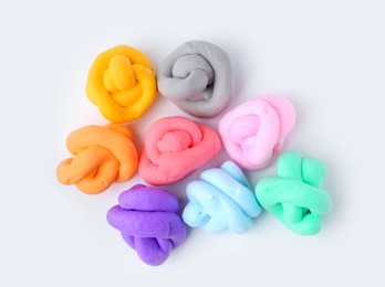 Photo of Different colorful play dough on white background, flat lay