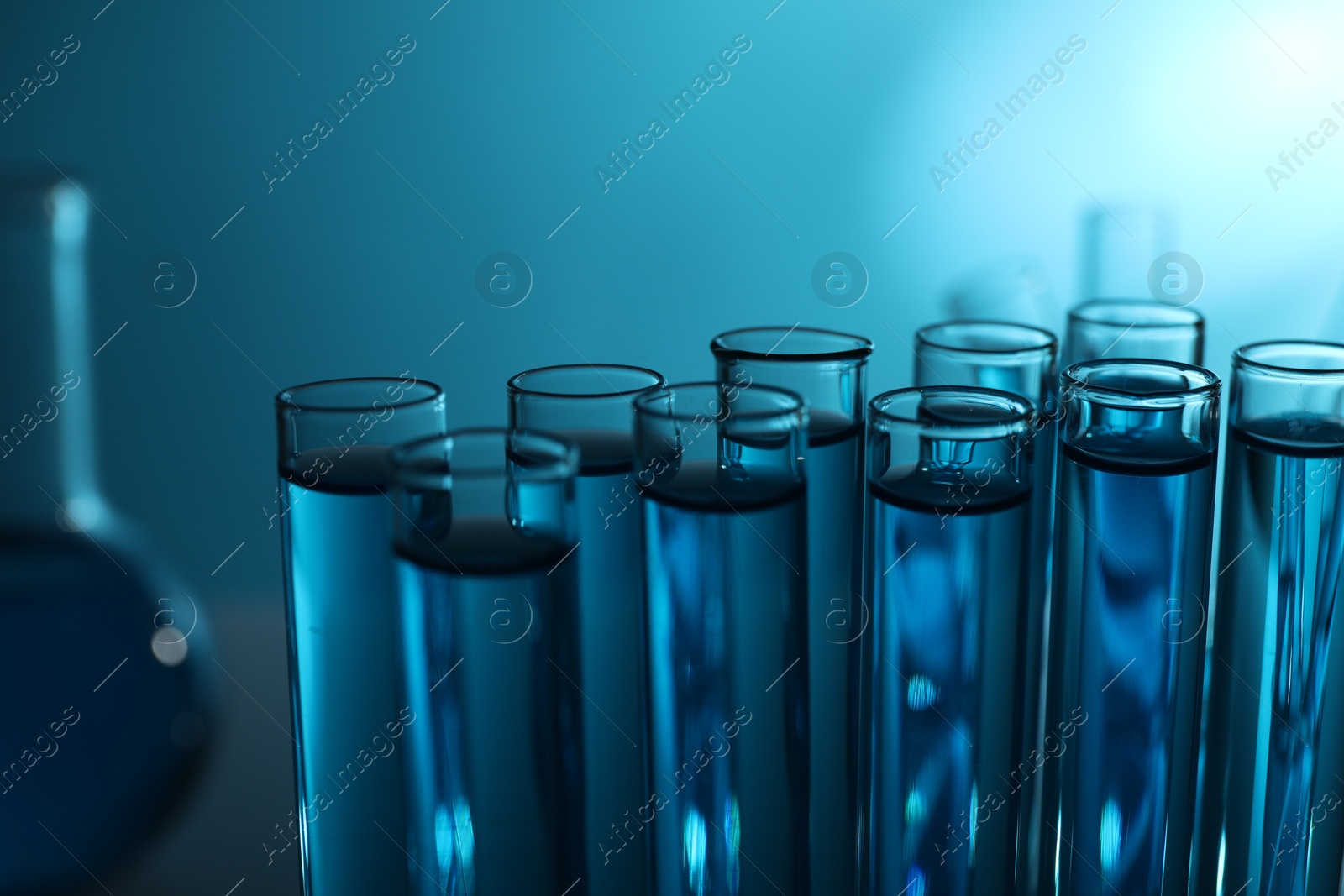 Photo of Test tubes with liquid on blue background, closeup. Color toned effect