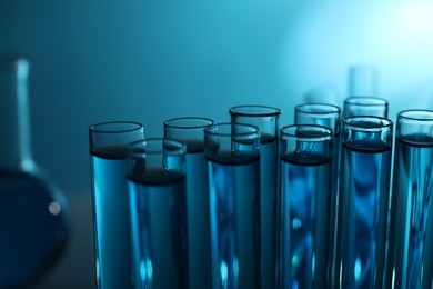 Photo of Test tubes with liquid on blue background, closeup. Color toned effect