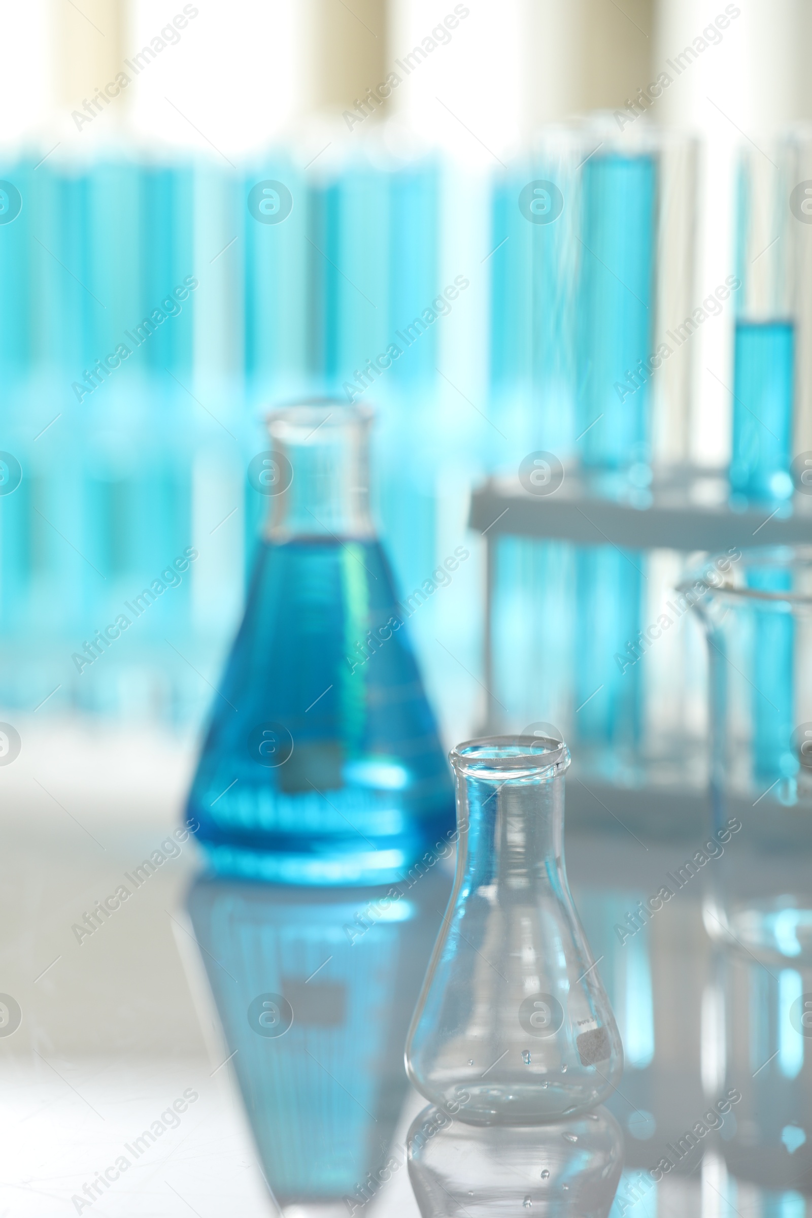 Photo of Laboratory glassware with liquid on mirror surface indoors