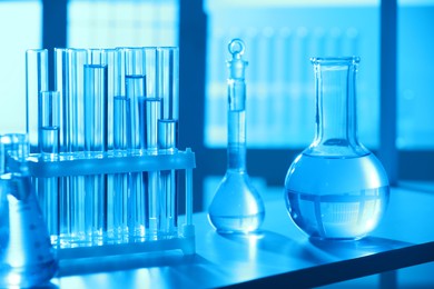 Photo of Laboratory glassware with liquid on shelf indoors. Color toned effect