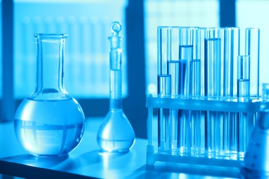 Photo of Laboratory glassware with liquid on shelf indoors. Color toned effect