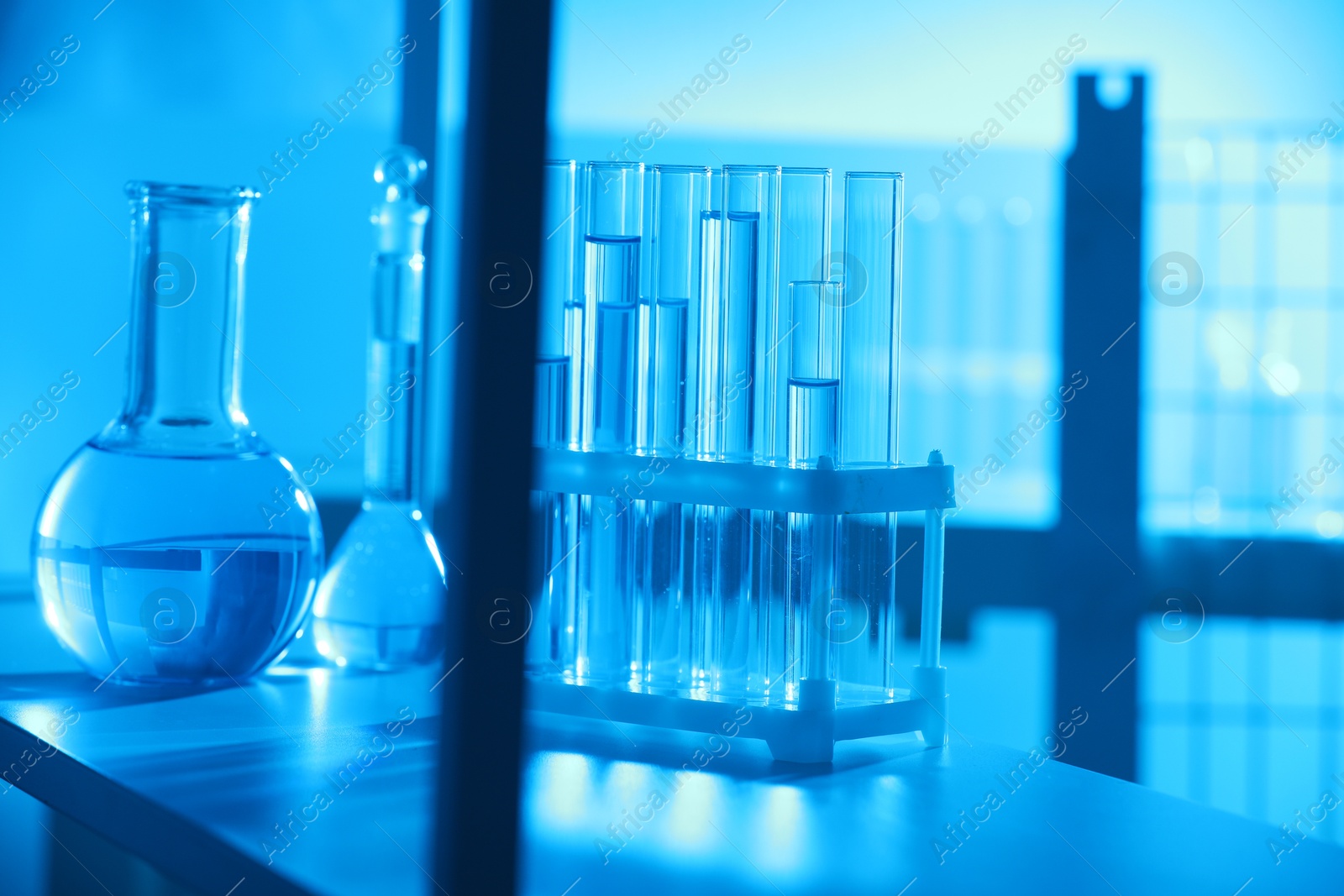 Photo of Laboratory glassware with liquid on shelf indoors. Color toned effect