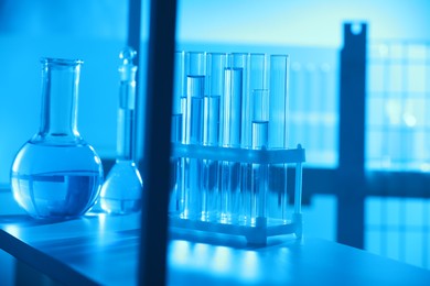 Photo of Laboratory glassware with liquid on shelf indoors. Color toned effect