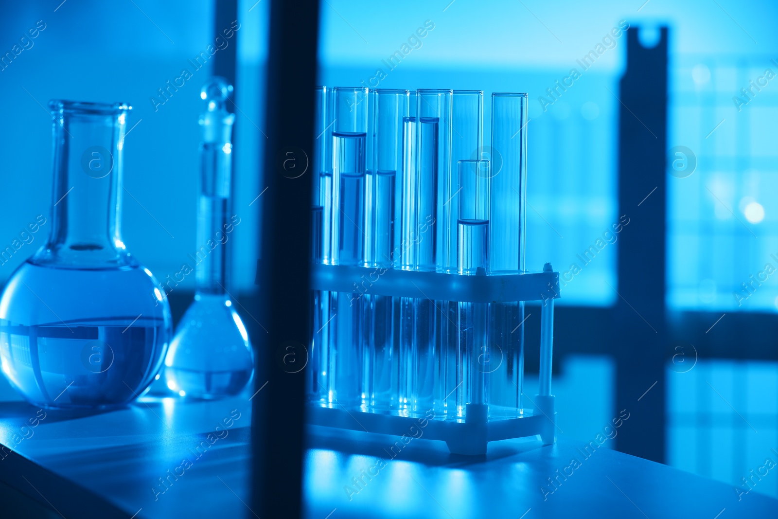 Photo of Laboratory glassware with liquid on shelf indoors. Color toned effect