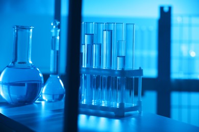 Photo of Laboratory glassware with liquid on shelf indoors. Color toned effect