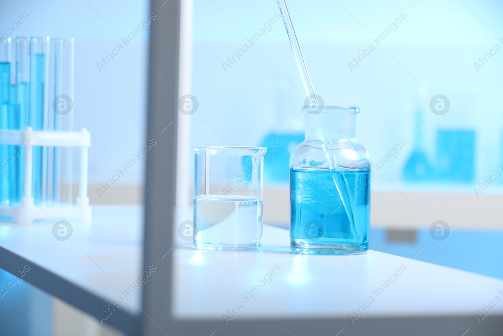 Photo of Laboratory glassware with liquid on shelf indoors