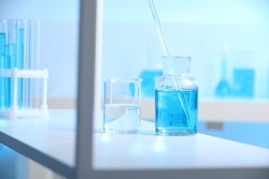 Photo of Laboratory glassware with liquid on shelf indoors