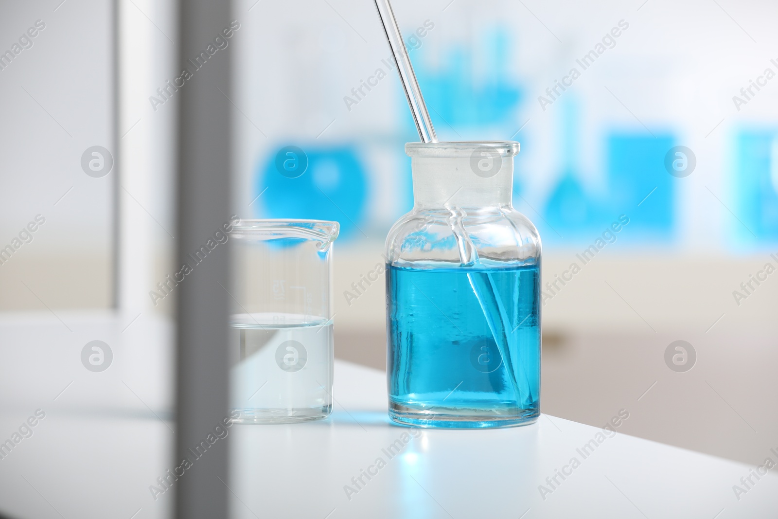 Photo of Laboratory glassware with liquid on shelf indoors