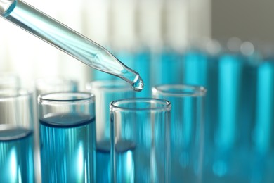 Photo of Dripping liquid into test tubes on light background, closeup