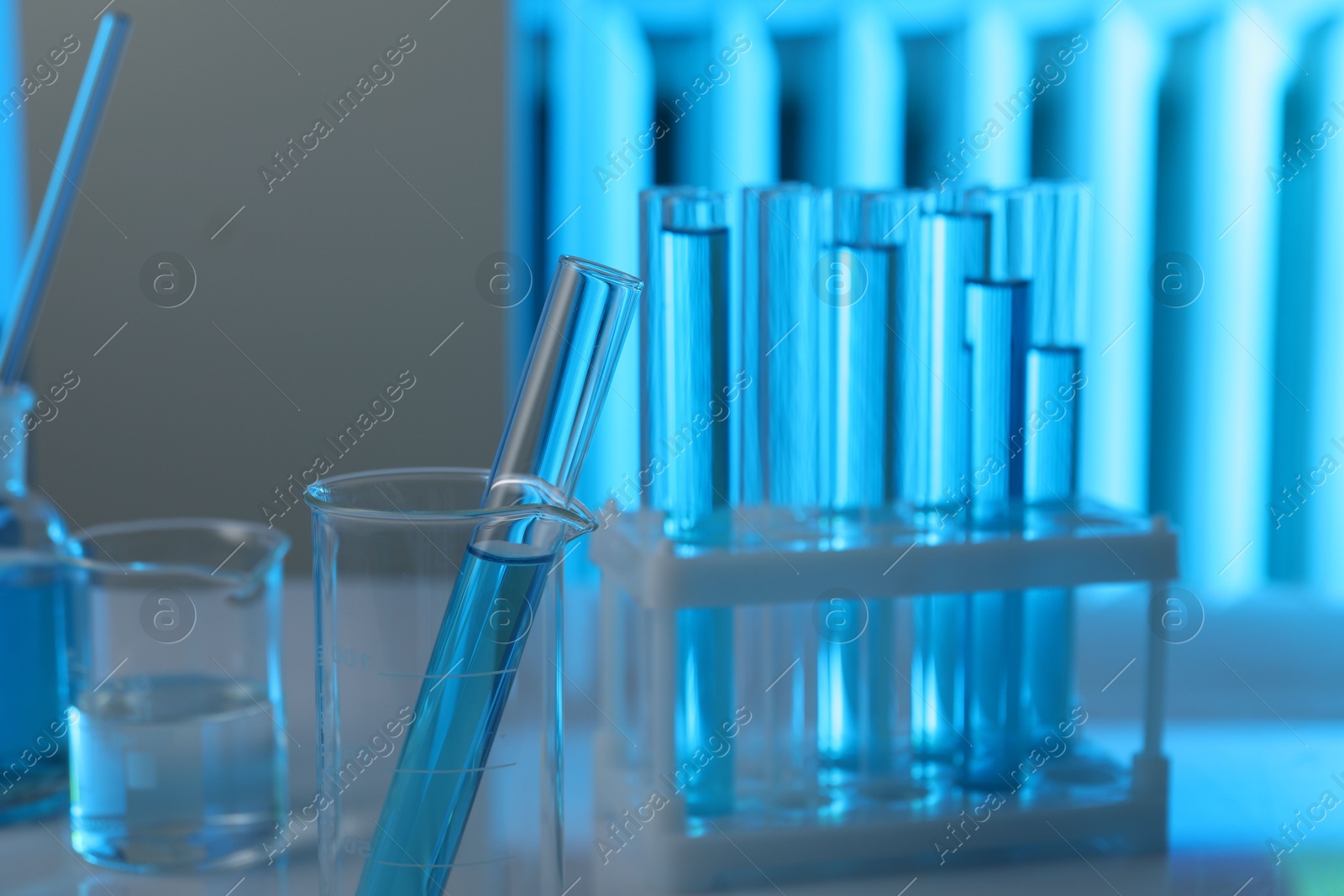 Photo of Laboratory glassware with liquid on table indoors, closeup