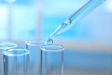 Photo of Dripping liquid into test tubes on light background, closeup