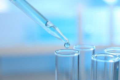 Photo of Dripping liquid into test tubes on light background, closeup