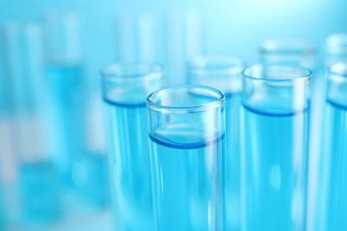 Photo of Test tubes with blue liquid on blurred background, closeup