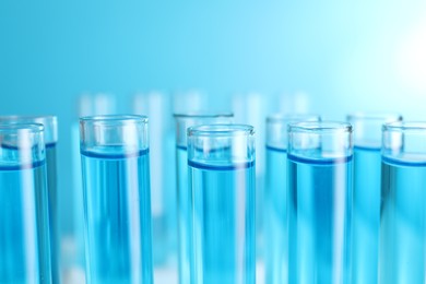 Photo of Test tubes with blue liquid on blurred background, closeup