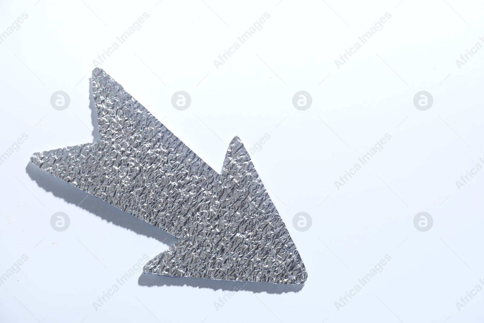 Photo of Silver tinfoil arrow on white background, top view. Space for text