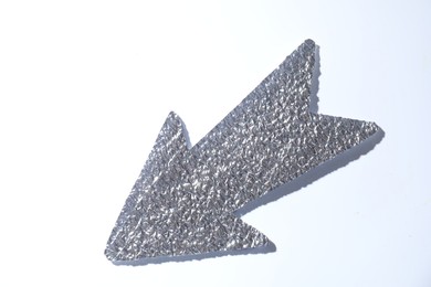 Photo of Silver tinfoil arrow on white background, top view