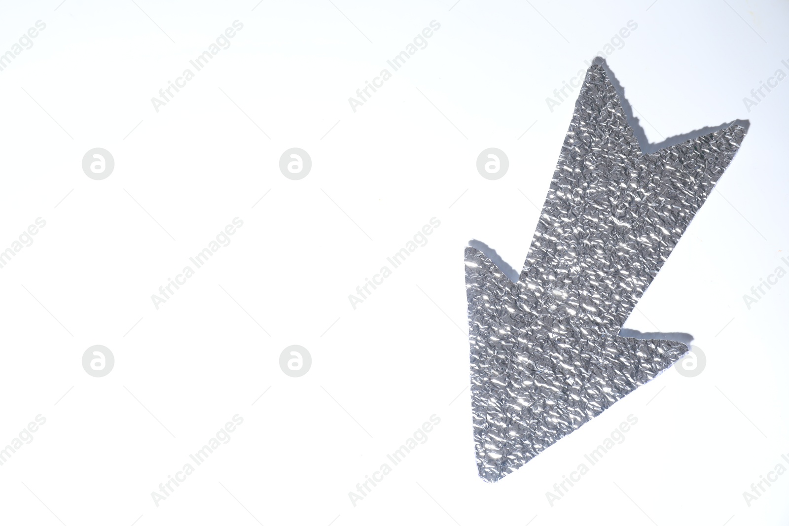 Photo of Silver tinfoil arrow on white background, top view. Space for text