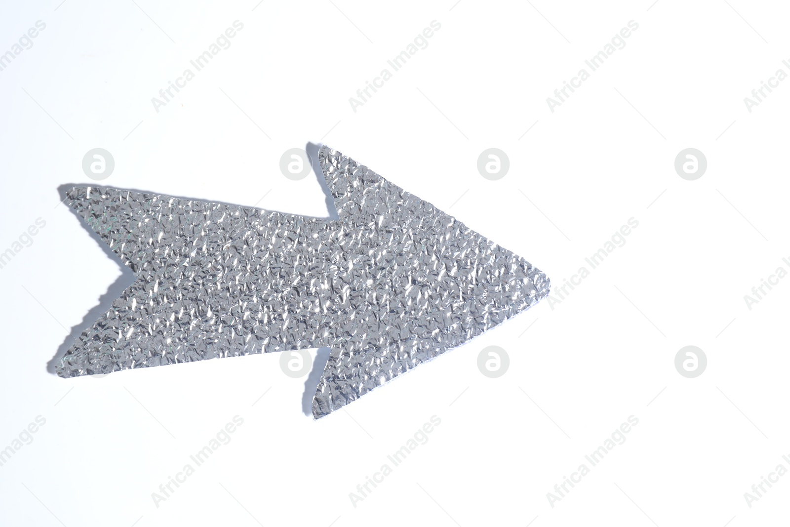 Photo of Silver tinfoil arrow on white background, top view. Space for text