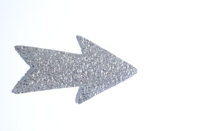 Photo of Silver tinfoil arrow on white background, top view. Space for text