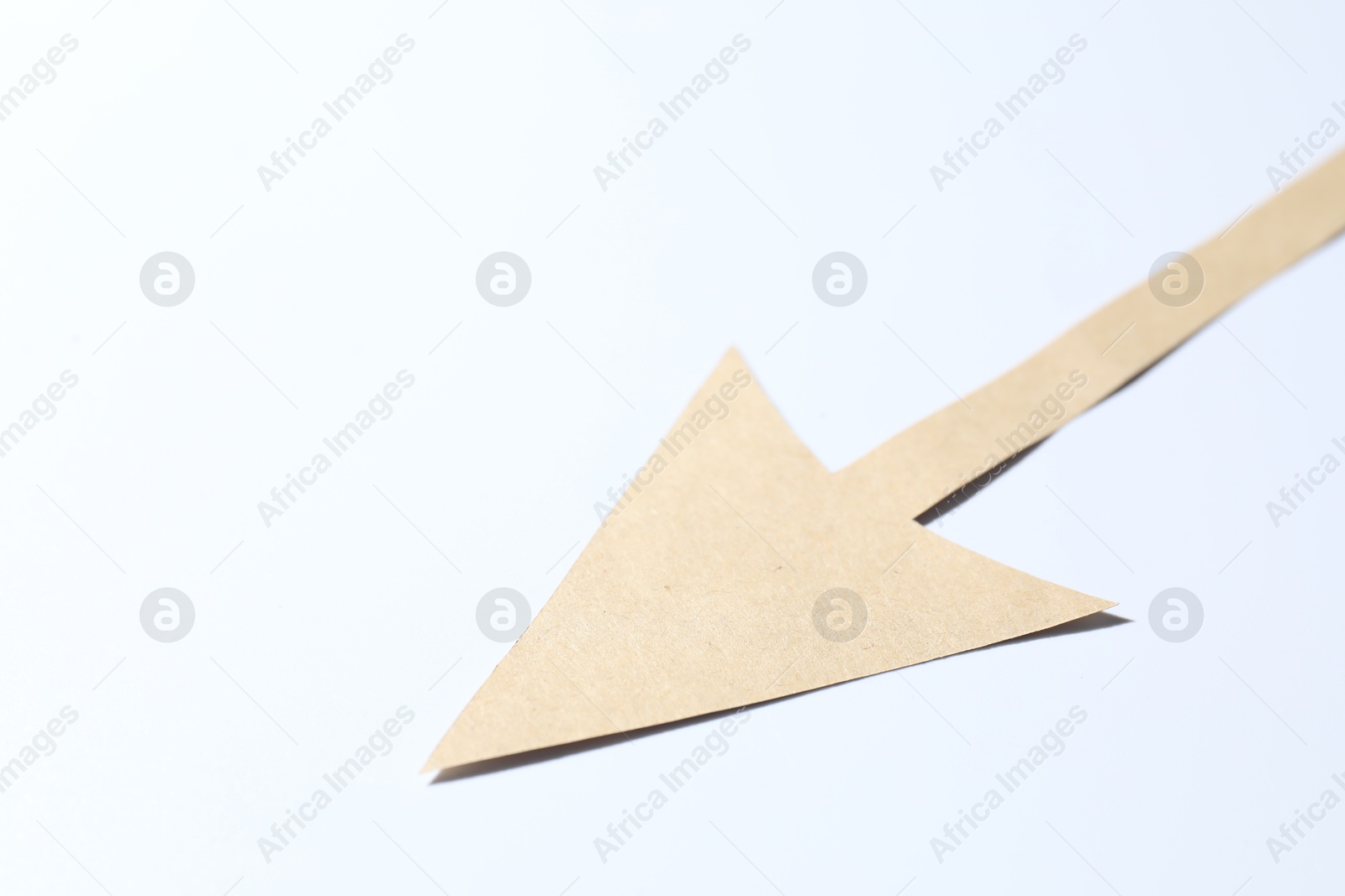 Photo of One kraft paper arrow on white background, closeup. Space for text