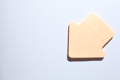 Photo of One orange paper arrow on white background, top view. Space for text