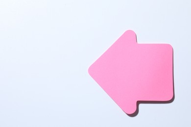 Photo of One pink paper arrow on white background, top view. Space for text