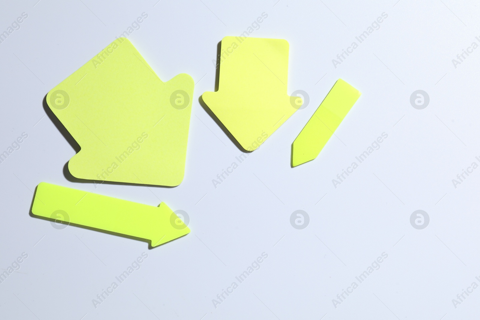 Photo of Yellow paper arrows on white background, flat lay. Space for text