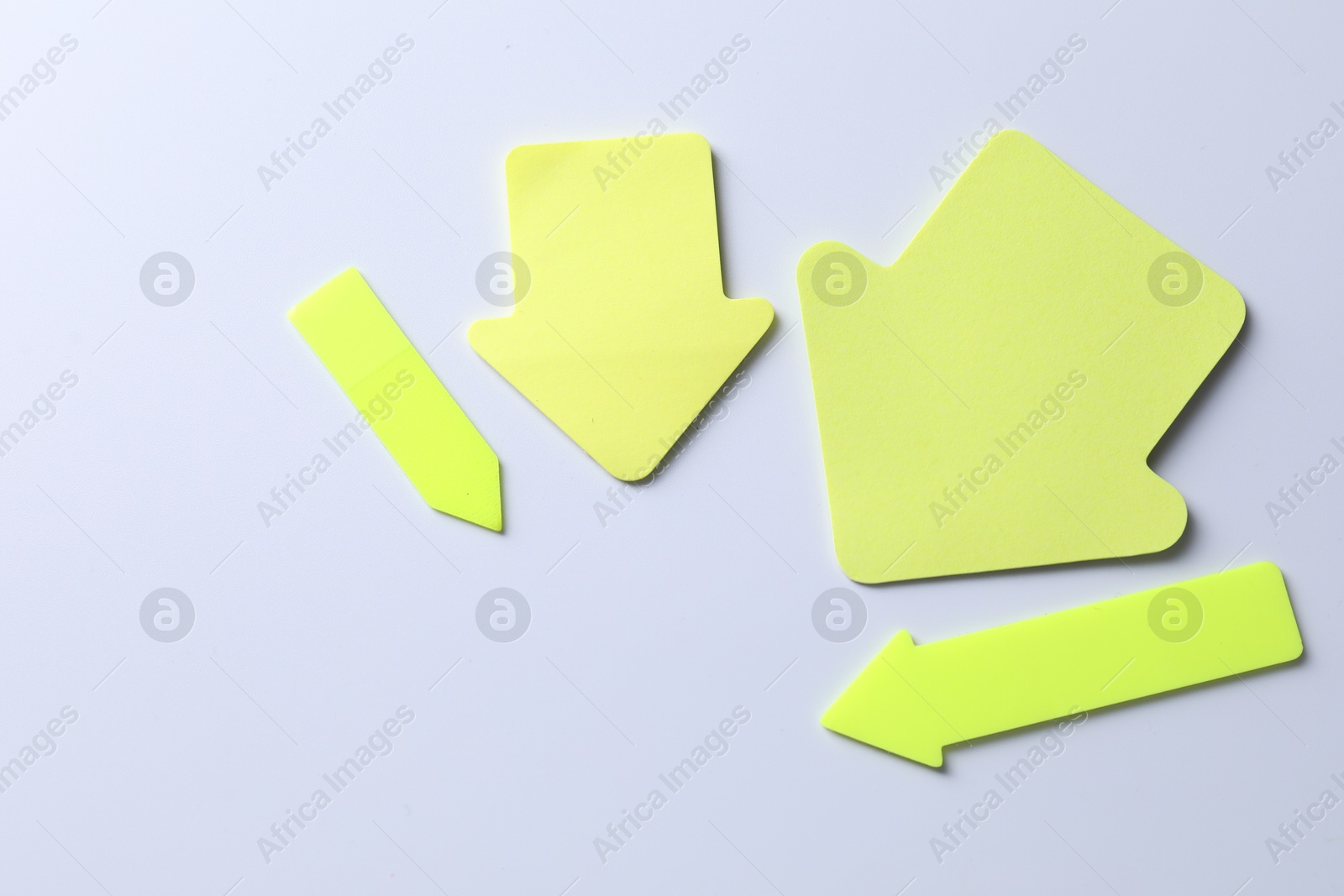 Photo of Yellow paper arrows on white background, flat lay. Space for text