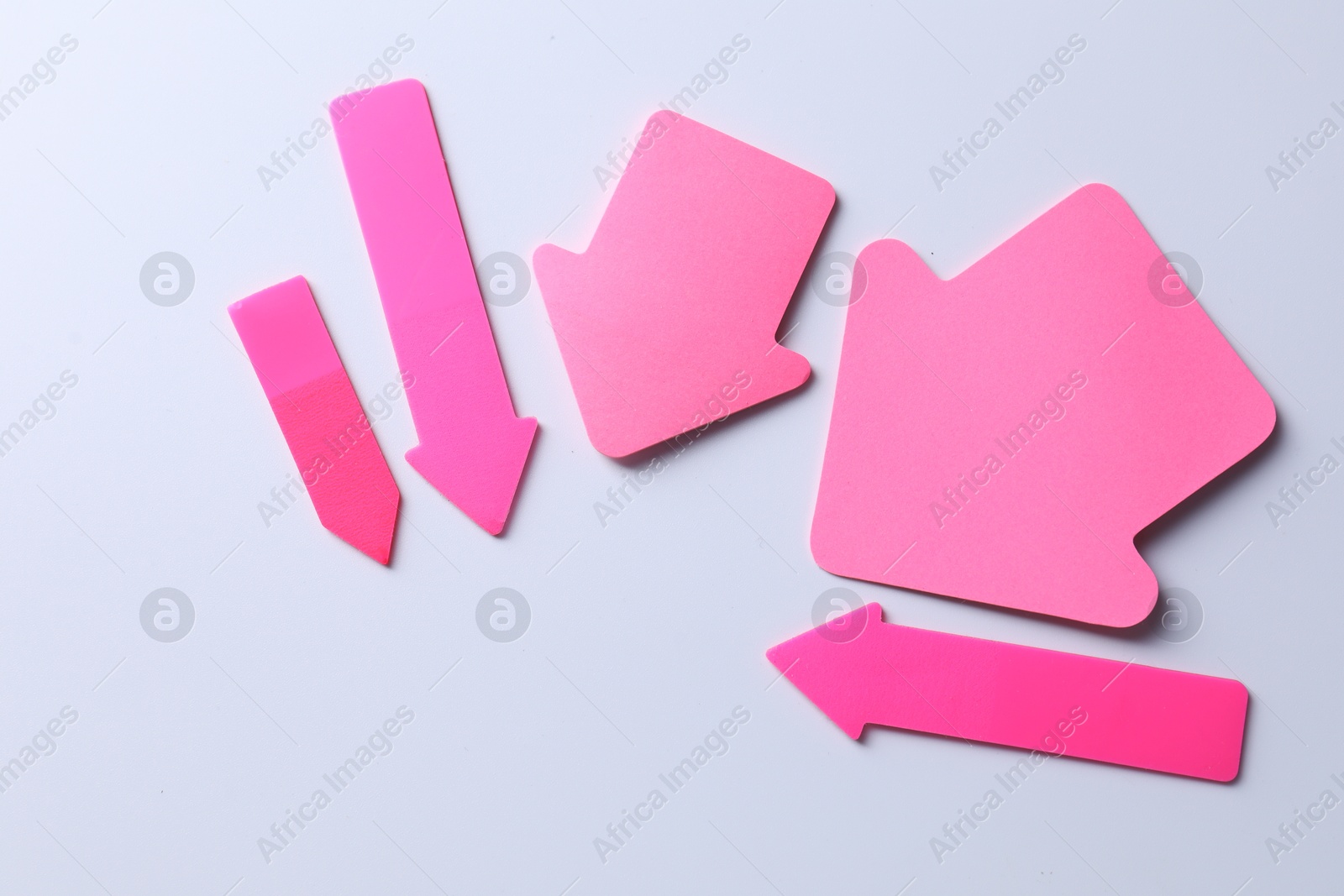 Photo of Pink paper arrows on white background, flat lay. Space for text