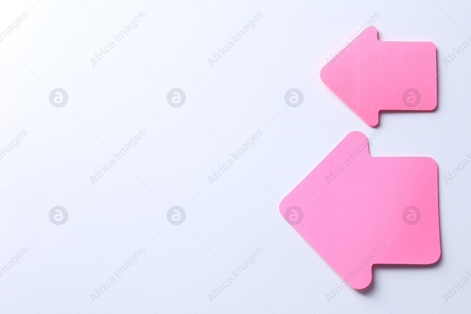 Photo of Pink paper arrows on white background, flat lay. Space for text