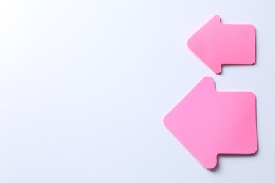 Photo of Pink paper arrows on white background, flat lay. Space for text