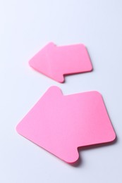 Photo of Pink paper arrows on white background, closeup