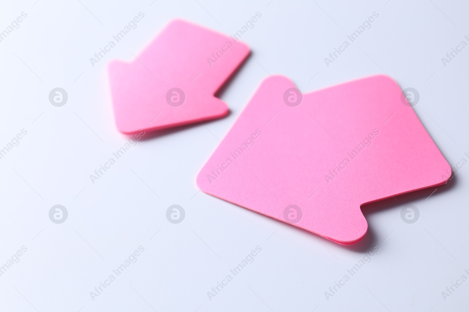 Photo of Pink paper arrows on white background, closeup