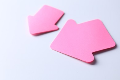 Photo of Pink paper arrows on white background, closeup