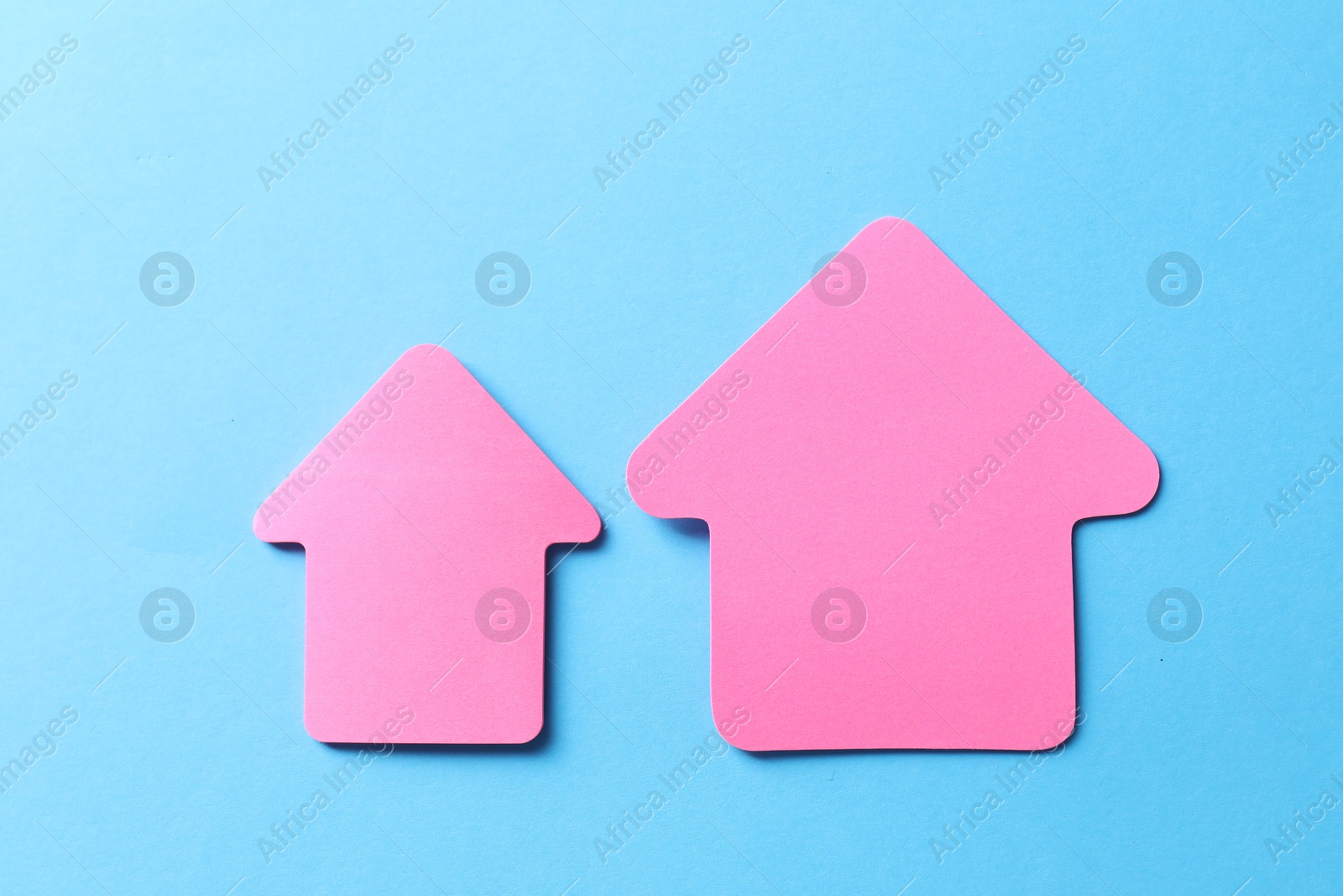 Photo of Pink paper arrows on light blue background, flat lay