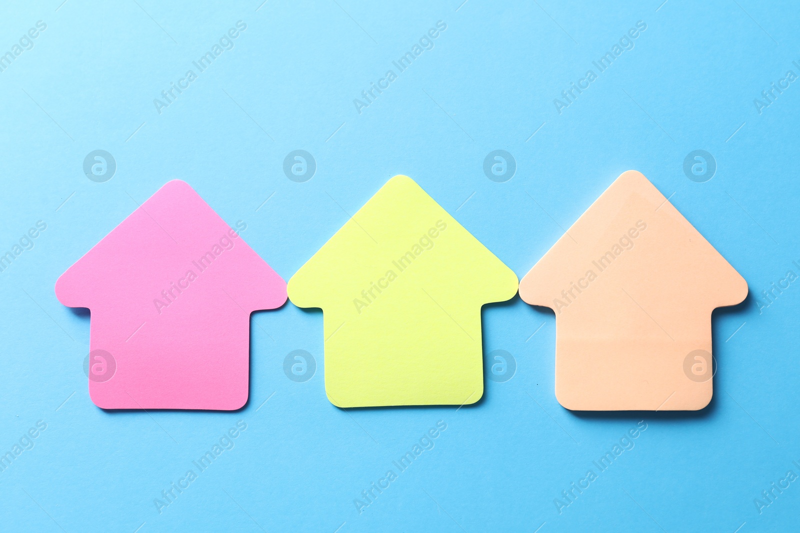 Photo of Colorful paper arrows on light blue background, flat lay