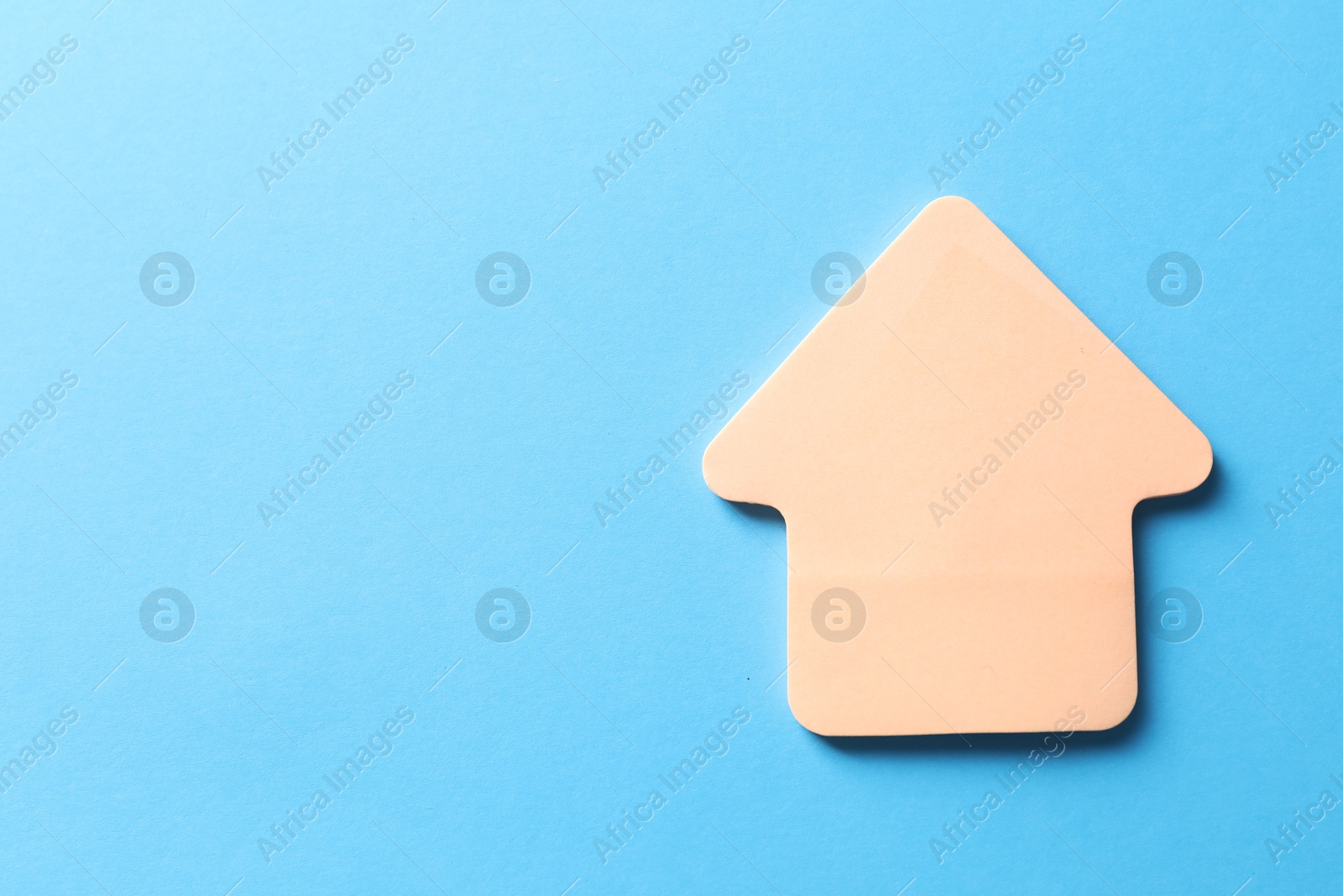 Photo of One color paper arrow on light blue background, top view. Space for text