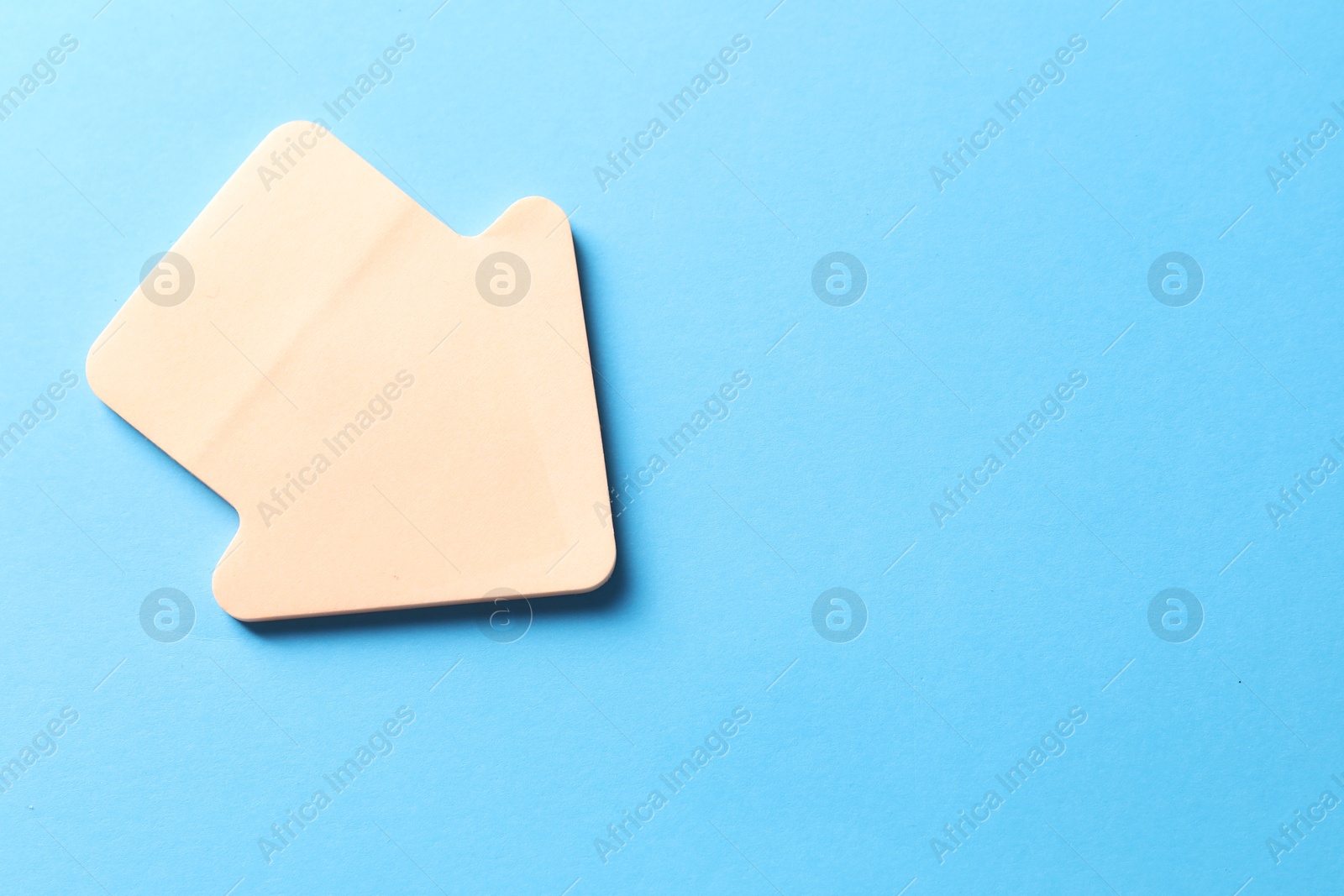 Photo of One color paper arrow on light blue background, top view. Space for text