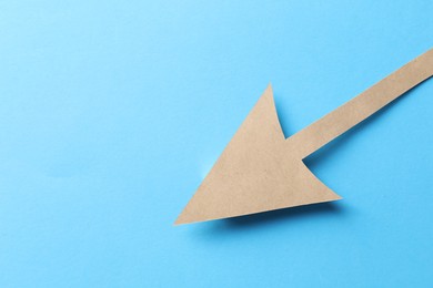 Photo of One kraft paper arrow on light blue background, top view. Space for text