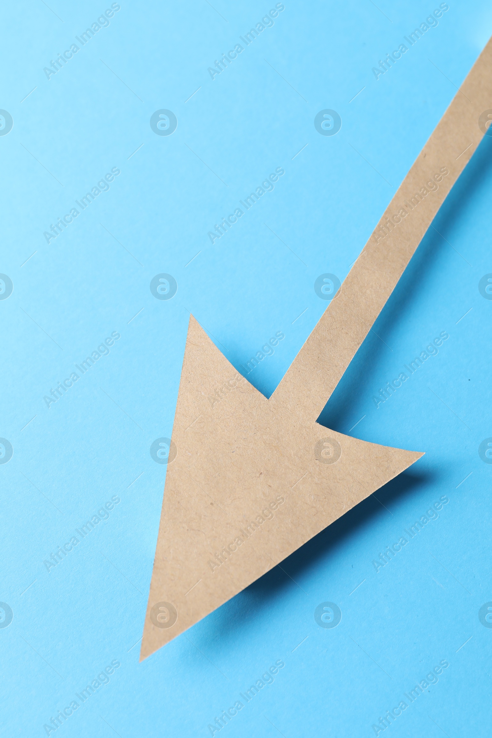 Photo of One kraft paper arrow on light blue background, top view