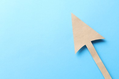 Photo of One kraft paper arrow on light blue background, top view. Space for text