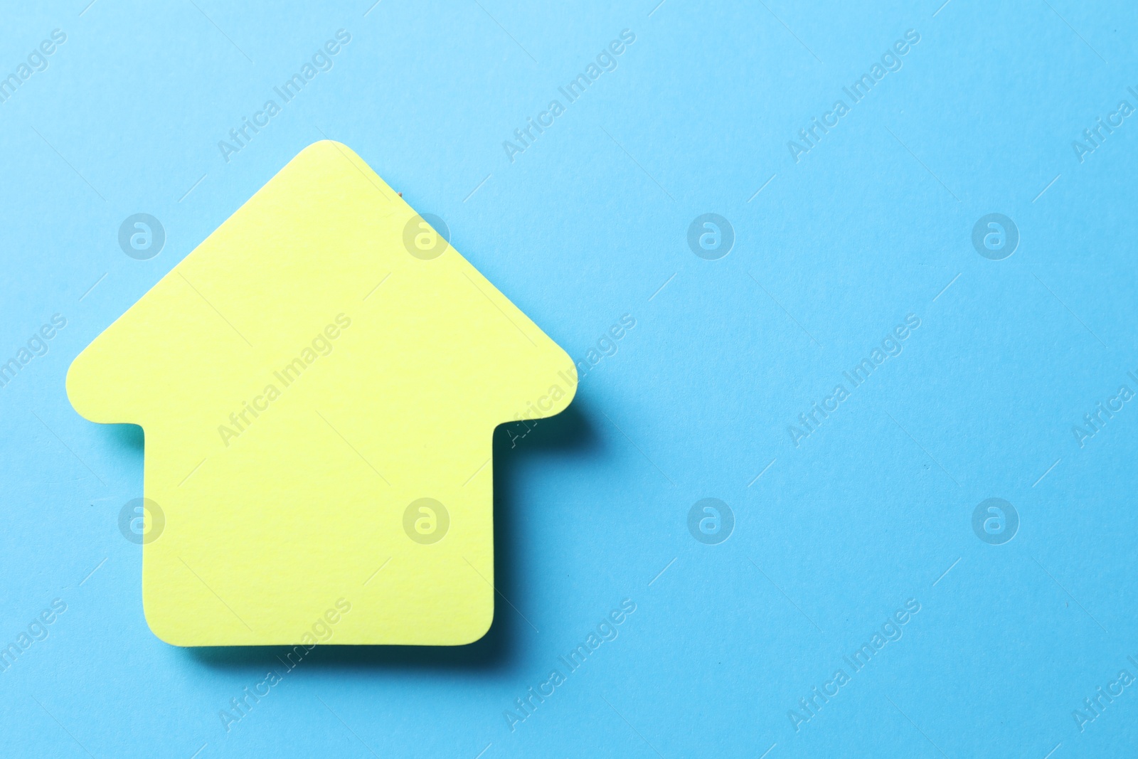 Photo of One color paper arrow on light blue background, top view. Space for text