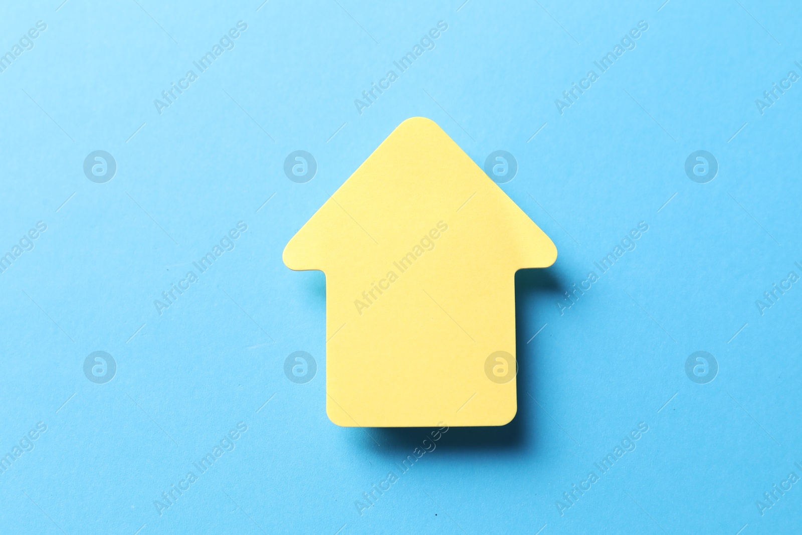 Photo of One yellow paper arrow on light blue background, top view