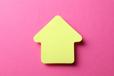 Photo of One yellow paper arrow on pink background, top view