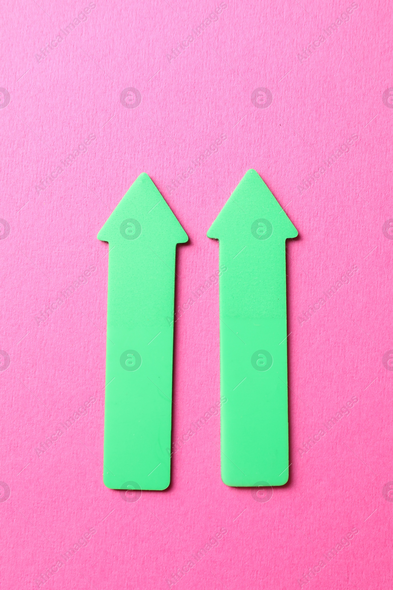 Photo of Green arrows on pink background, top view