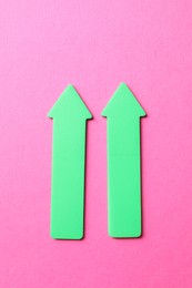 Photo of Green arrows on pink background, top view